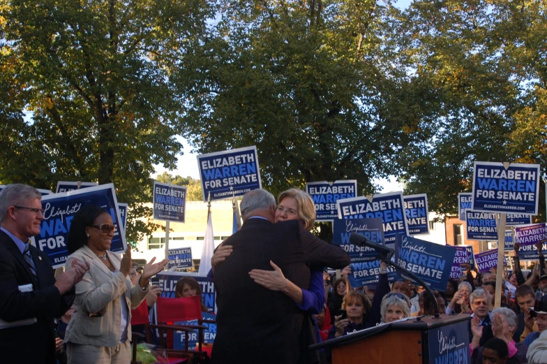 a man and woman hugging during a campaign in front of an audience
