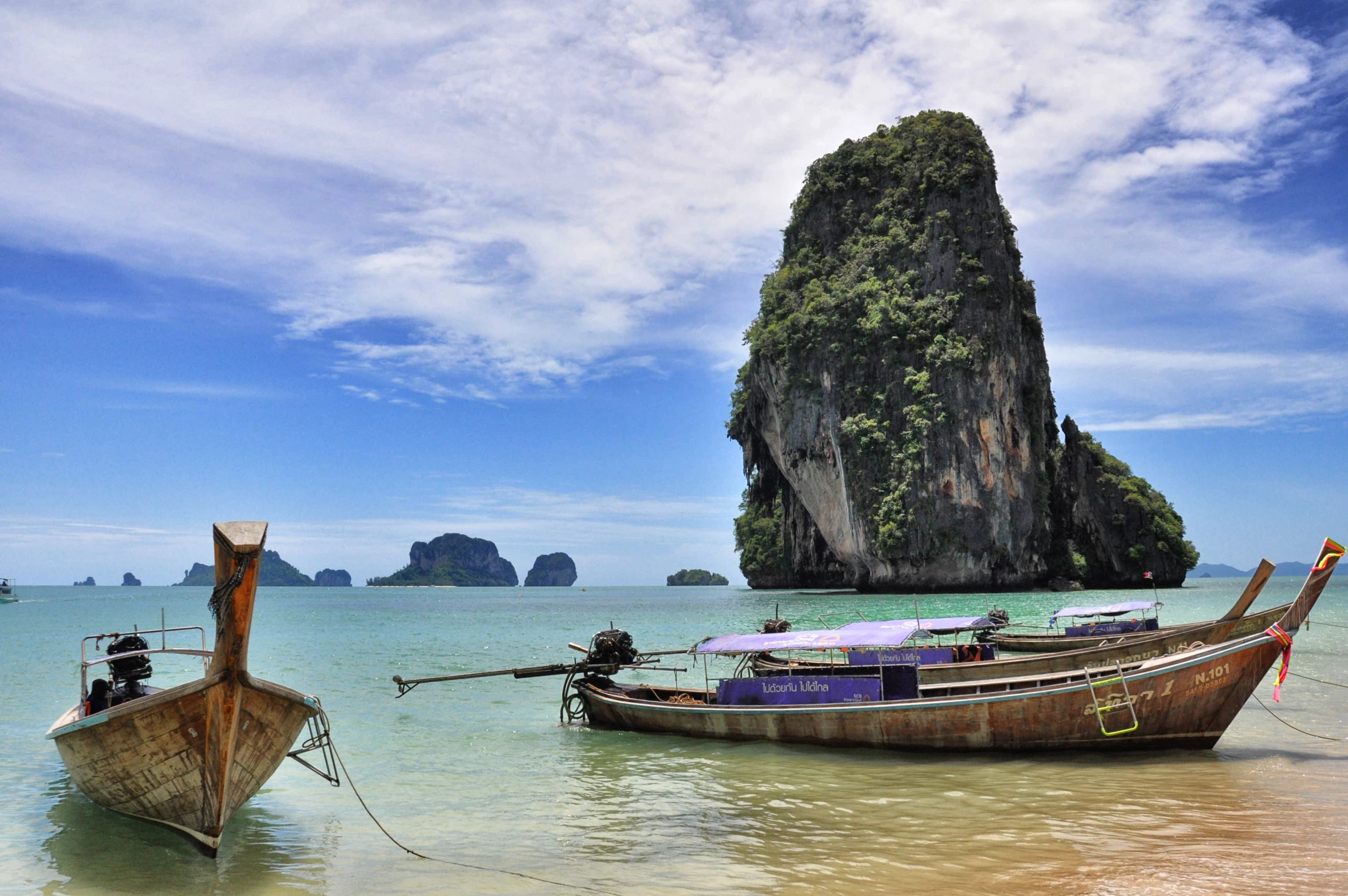 two boats floating in a lake next to a rocky shore