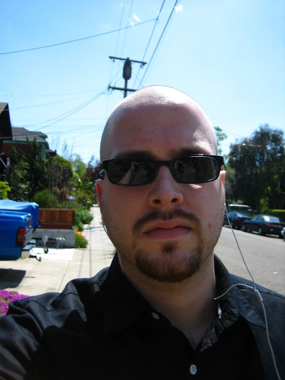 a bald man wearing sunglasses next to a road