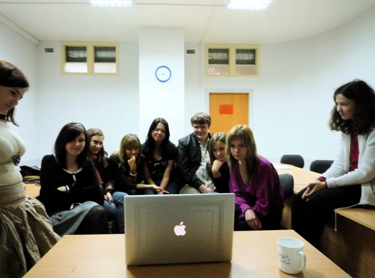 a group of young students sitting around a laptop