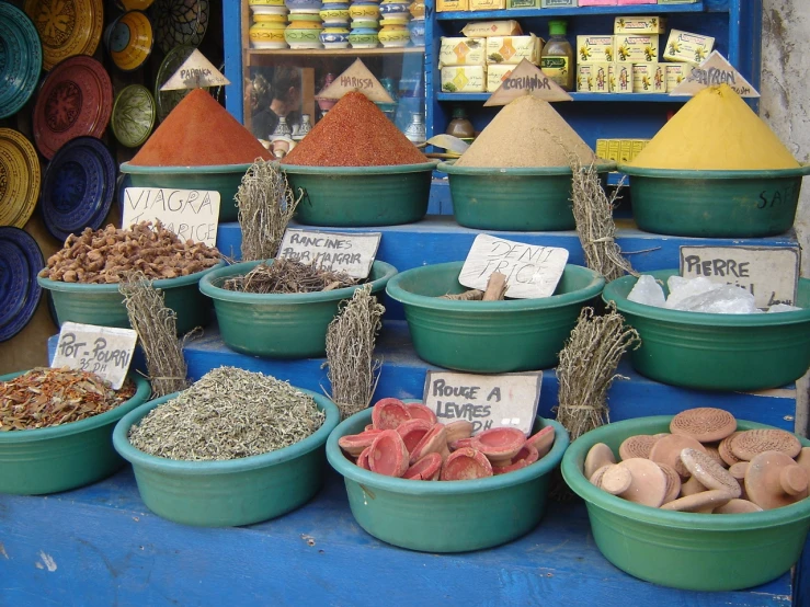 bowls and bowls of spices are in front of blue shelves