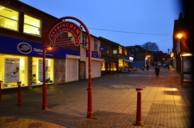 an empty shopping street at night with people walking by