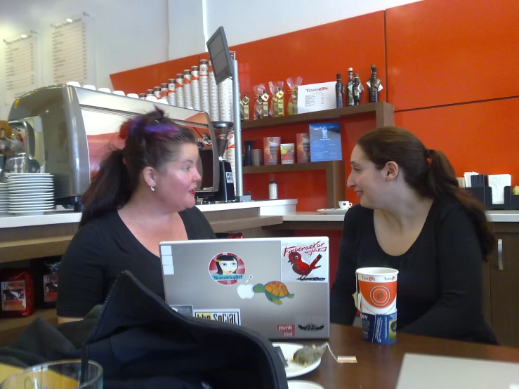 two woman in a restaurant setting looking at their laptop computer