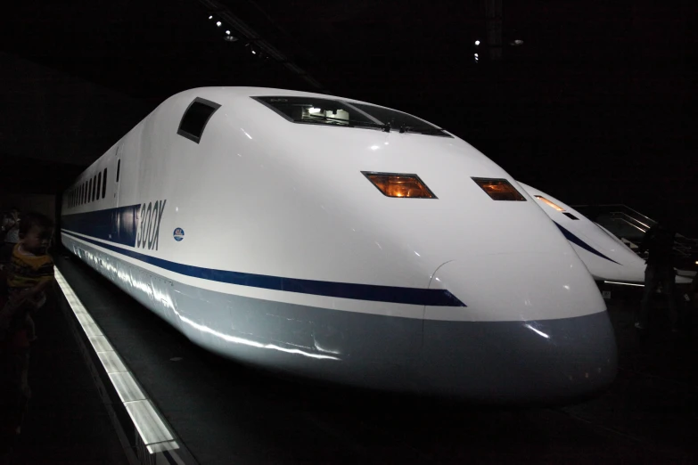 a white and blue bullet train is seen at night