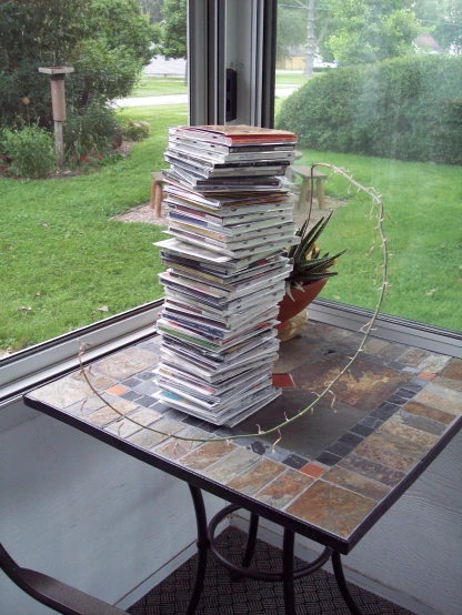 a stack of magazines on a glass table by a window