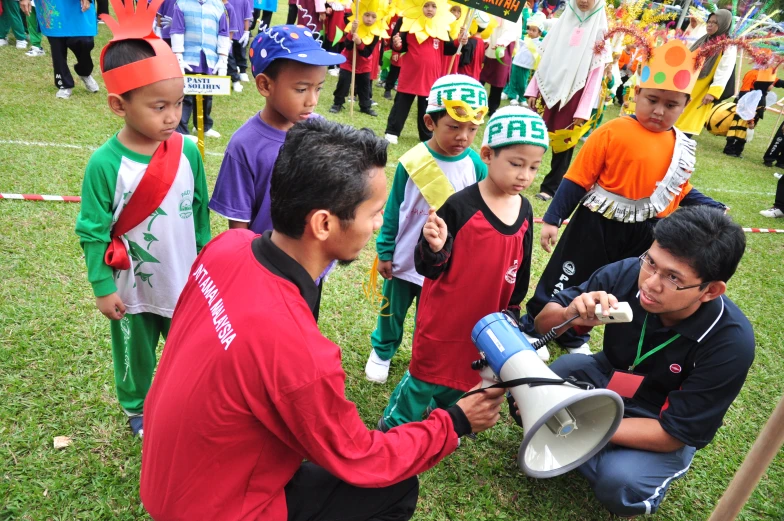 some children are holding up flags and talking to a man