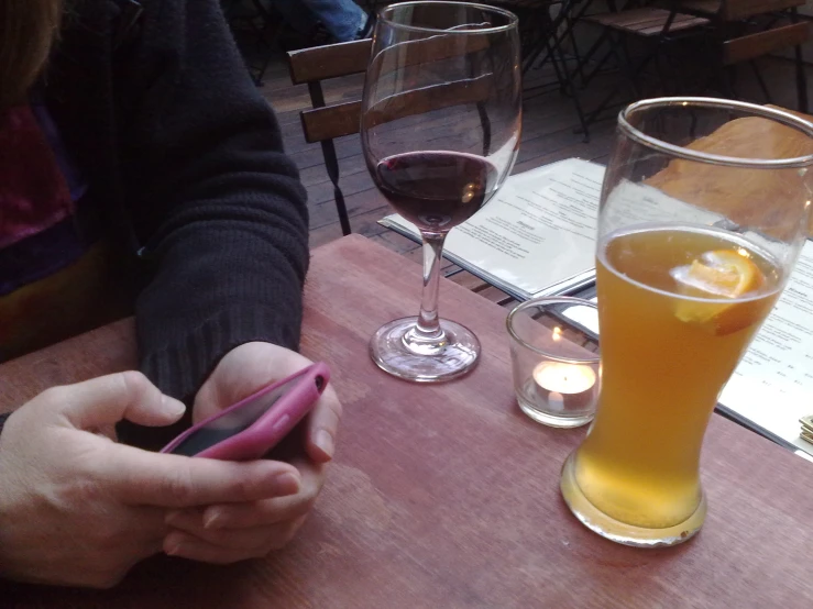 a person holding a cell phone on a wooden table