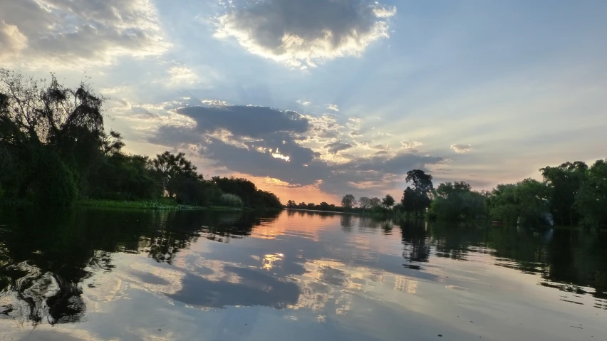 the water has many trees and clouds in it