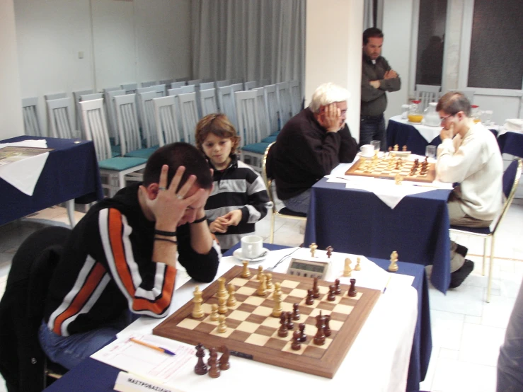 people sitting around tables playing chess on blue tables