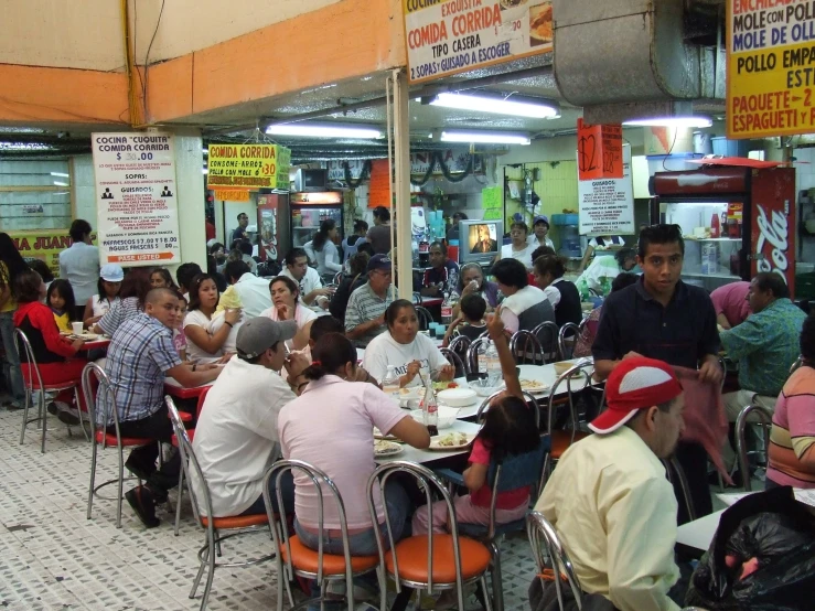 many people sit at tables in a food court