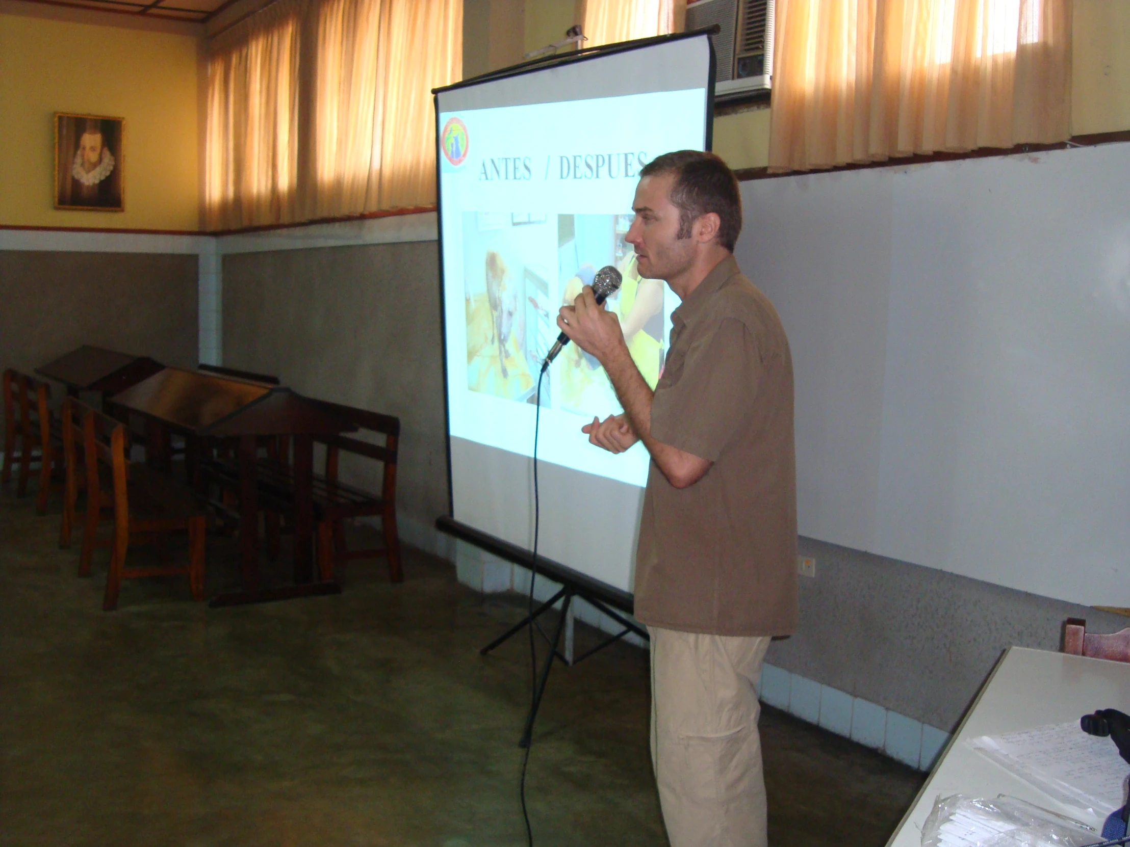 a man standing in front of a projected screen holding a microphone