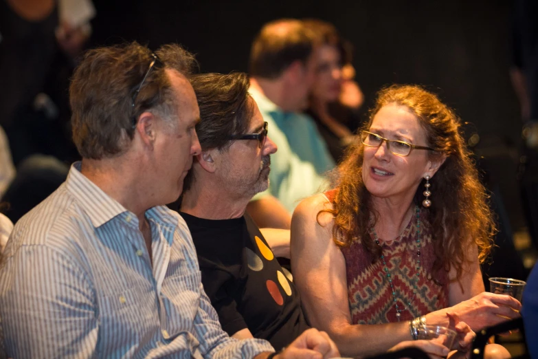 two men and a woman sitting together watching soing