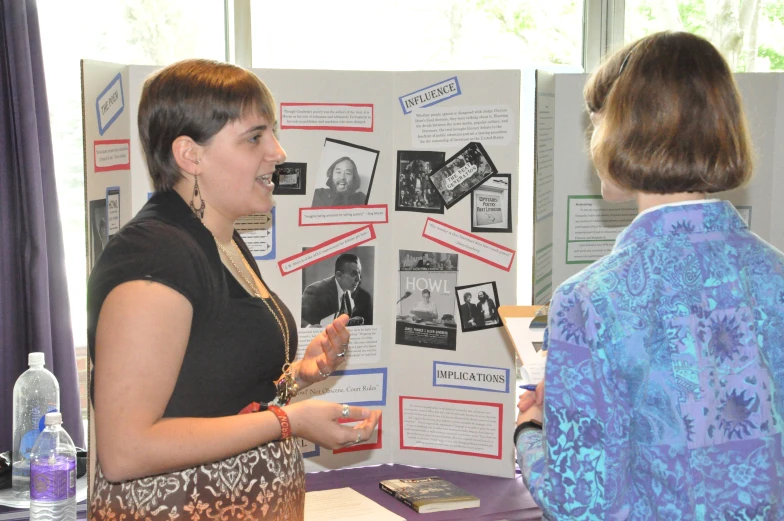 a woman talks to another woman in front of an advertit