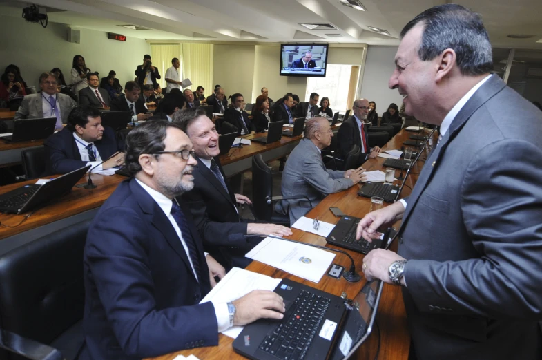 a man in business attire using a laptop while others watch