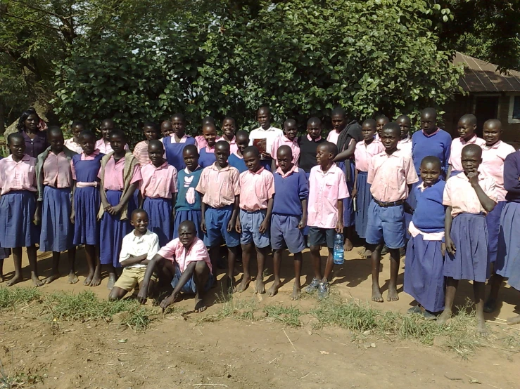 a group of children in pink shirts and blue skirts stand together