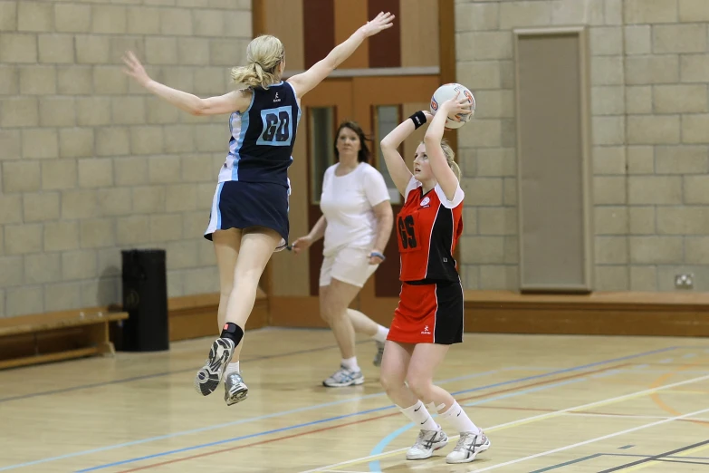 two girls jump high with one trying to catch the ball