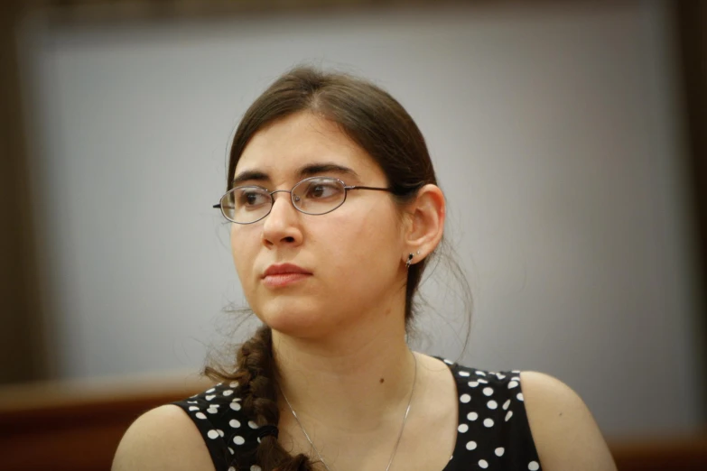 a girl wearing glasses looks ahead from her seat