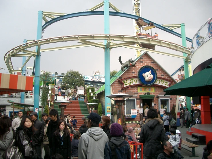 several people standing around near a building with an animal riding a roller coaster