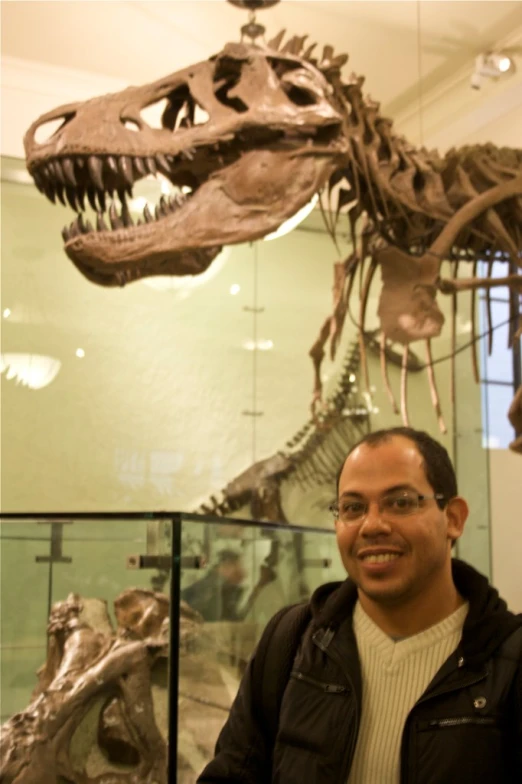 a man in glasses and jacket next to an image of a t - rex