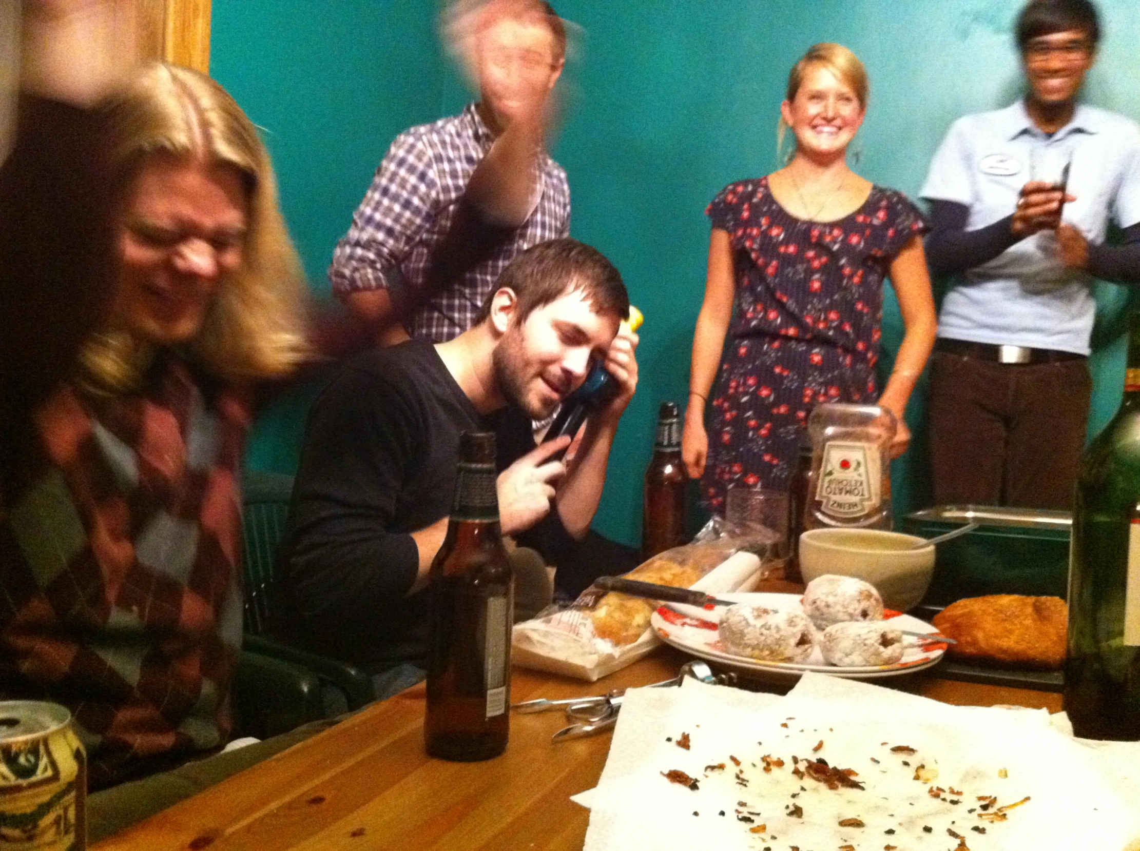 a group of people sitting around and laughing with bottles of wine