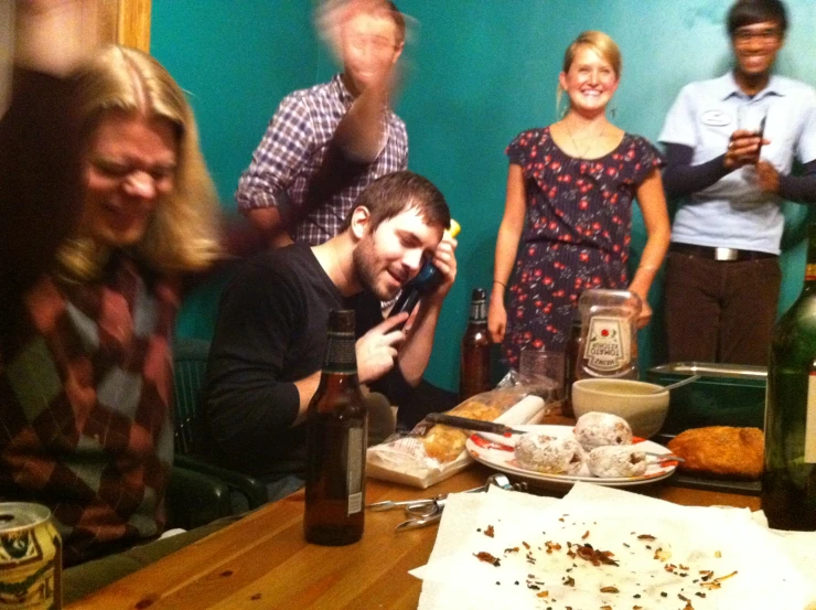 a group of people sitting around and laughing with bottles of wine