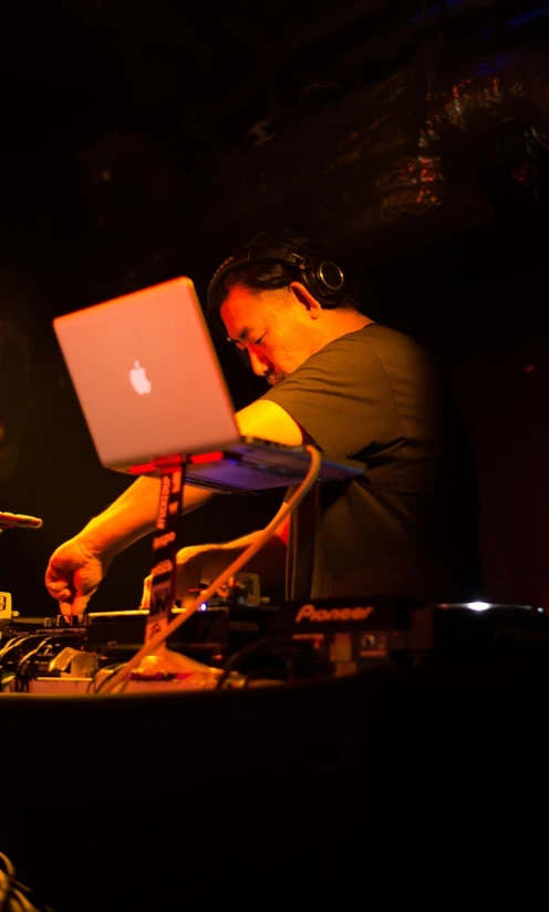 dj performing with laptop computer on table in dark lit area