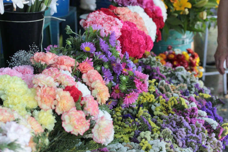 many different colorful flowers in buckets on a table