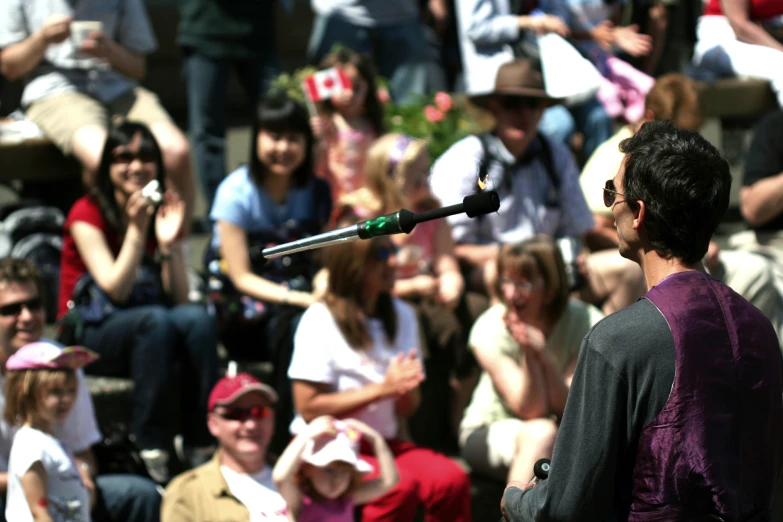 a man with glasses standing next to a microphone in front of a crowd