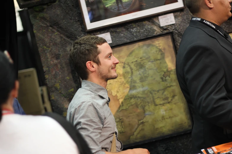 a man standing next to a table near a painting