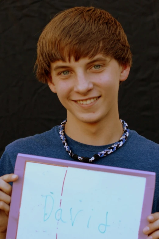 there is a young man that has a blue shirt and is holding a sign