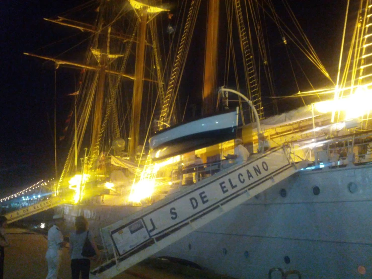 a large boat docked at night with some people on the deck