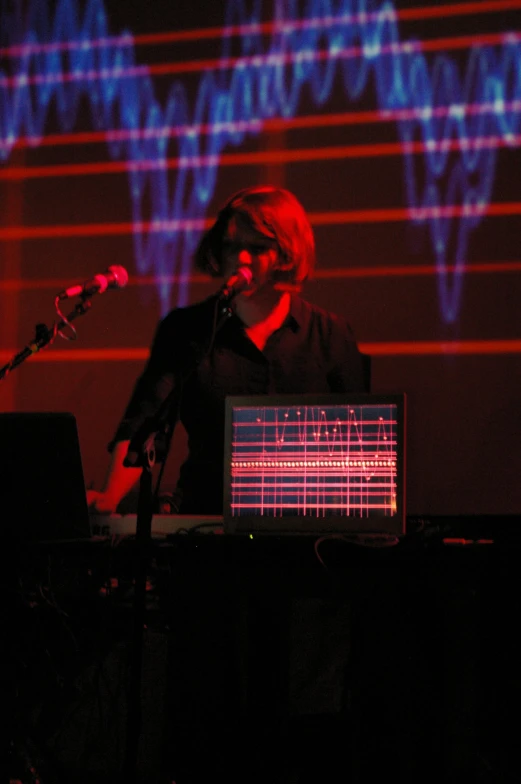 a man in front of a laptop at night with microphone