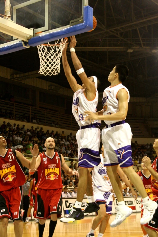 two men jump high to dunk the basketball