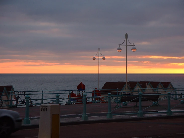 people sitting on the edge of a beach as the sun sets