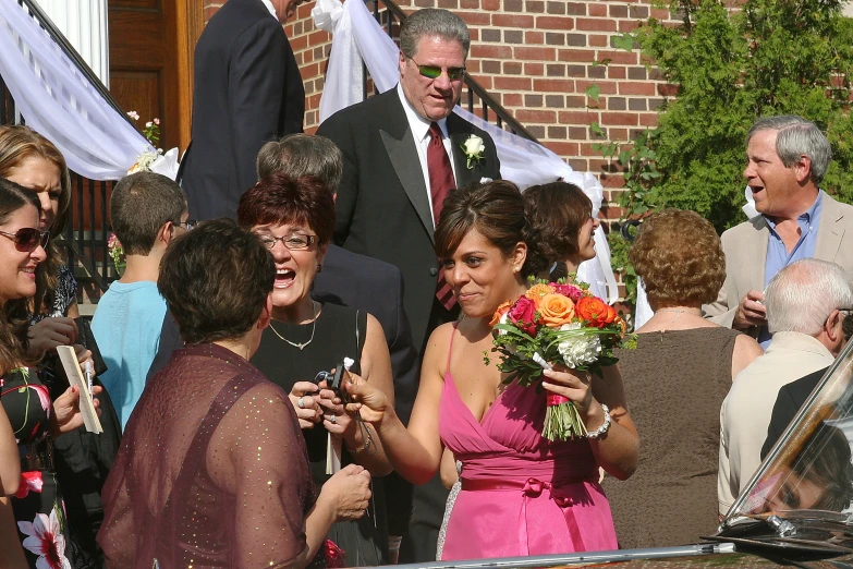 people talking outside while a woman in a pink dress has her hand on another woman's shoulder