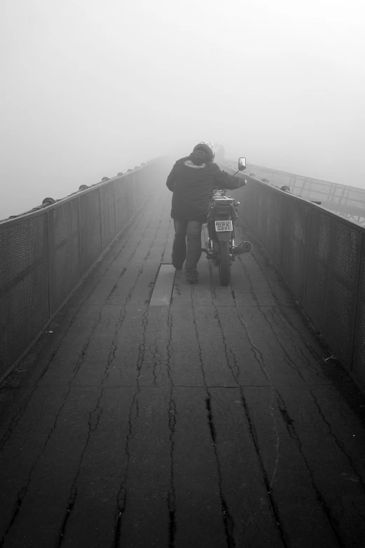 a man standing on a bridge in the fog