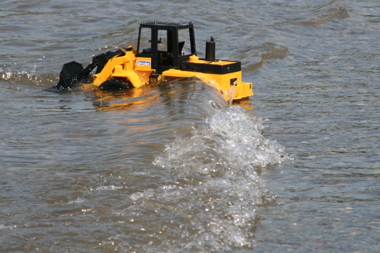 yellow bulldozer with hood of water coming out from it