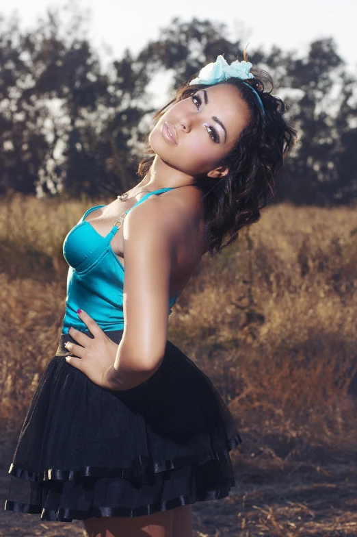 a woman posing in a blue top and black skirt