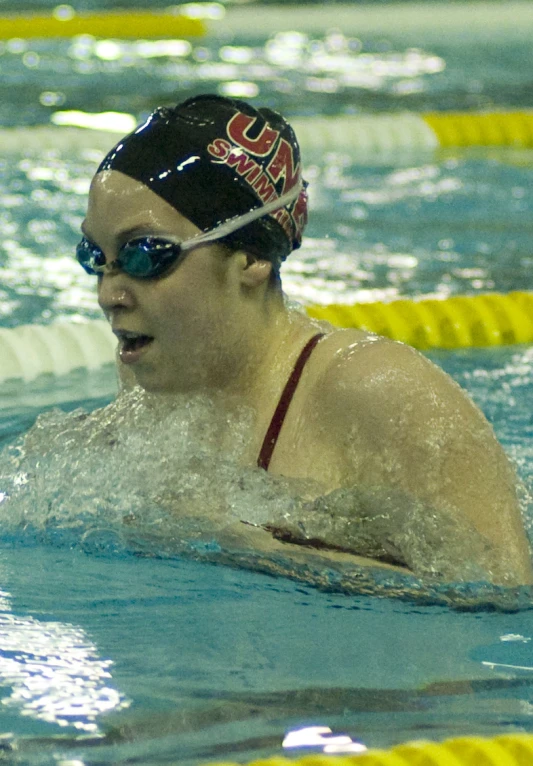 young adult swimmer in water wearing goggles and a headband