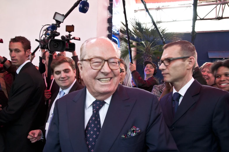 a man in a suit and tie standing with other people behind him