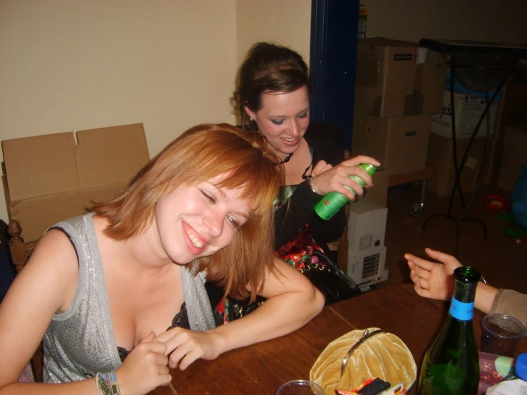 two women are smiling at the camera while one is pouring drinks