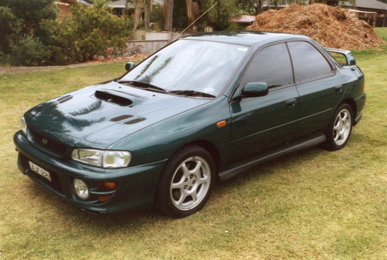 a green toyota celica sitting in a grassy yard