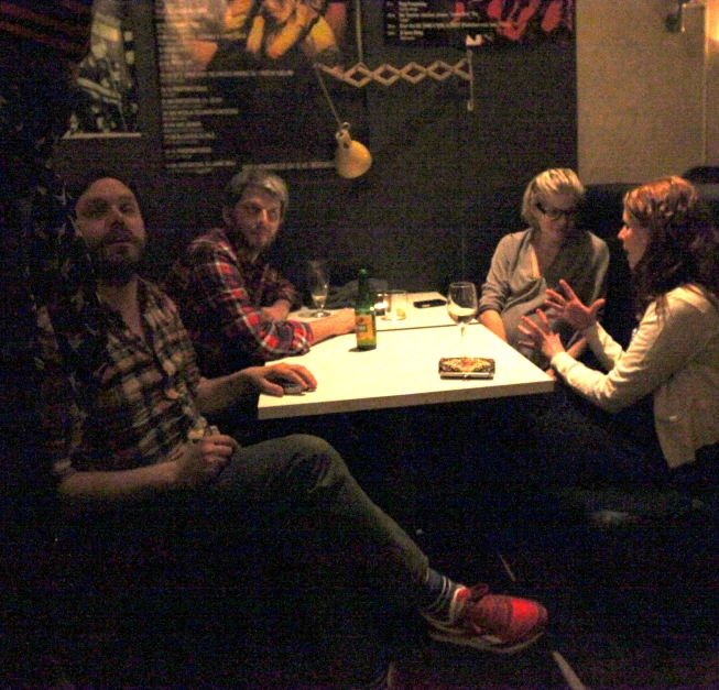 a group of people siting at a table with one person holding a bottle