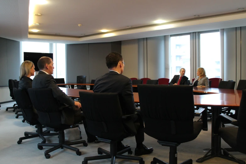 some business people in suits and ties are seated at a conference table