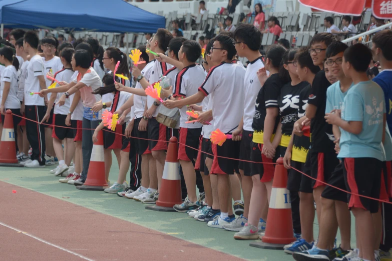 a long line of young men stand at a line of orange cones