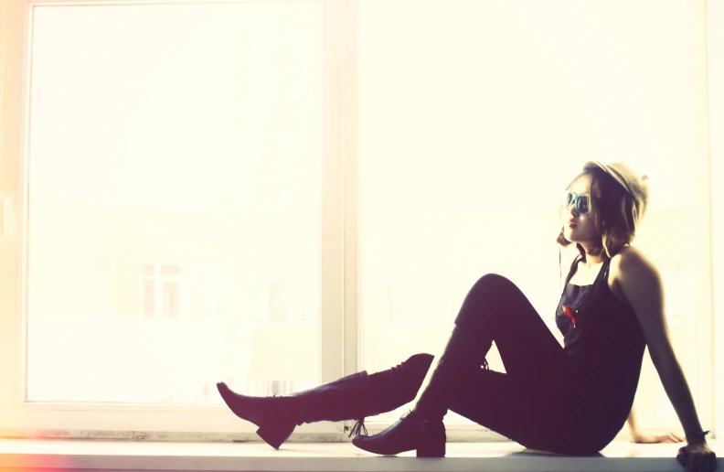 a beautiful young lady wearing high heeled shoes sitting in front of a window