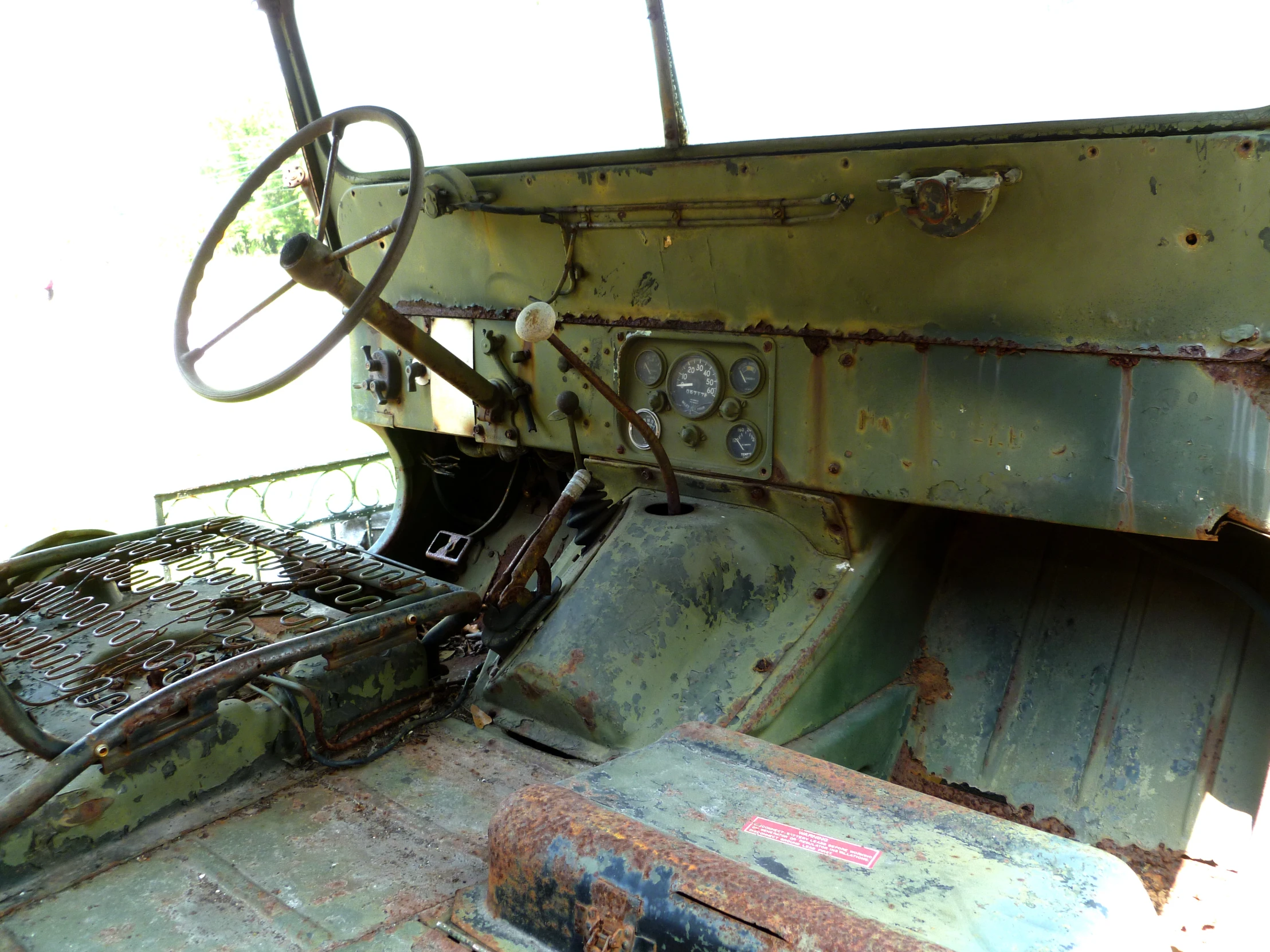 an old green vehicle has metal parts and steering wheel,