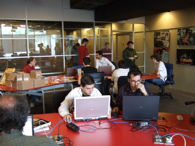 people sitting at tables in an office with two laptop computers