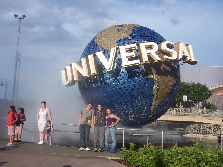 four people standing in front of the universal studios sign