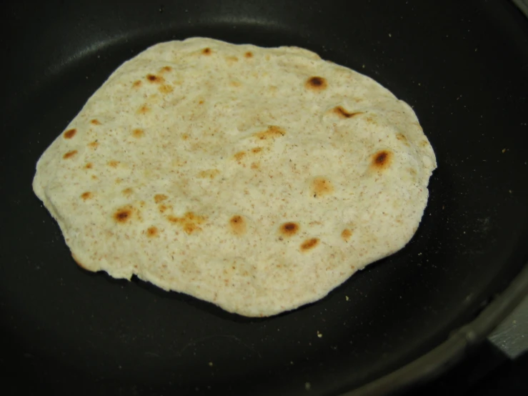a flat bread in a black pan on a stove